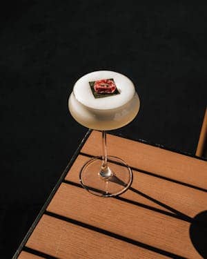 Stylish cocktail garnished with floral decor on a sunny outdoor table.